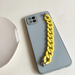 Detail of blue silicone phone case with chunky yellow acrylic chain and metal rivets
