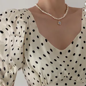 Detail of freshwater pearl necklace with round blue gemstone pendant on model