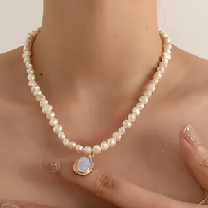 Detail of freshwater pearl necklace with gold-rimmed blue moonstone pendant on neck