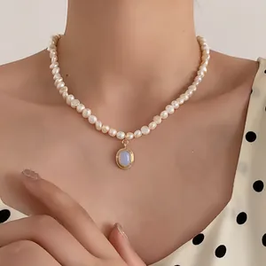 Detail of freshwater pearl necklace with vintage gold moonstone pendant on woman neck