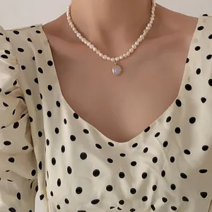 Detail of natural freshwater pearl necklace with a round blue moonstone pendant on a model
