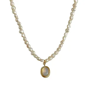 Baroque pearl necklace with a gold oval moonstone pendant on a white background