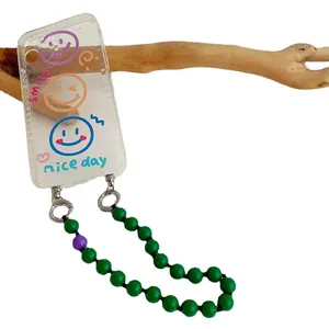 Smile face clear phone case with green beaded lanyard charm on wooden branch display