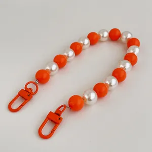 Detail of bright orange and pearl white beads on a lanyard with metal lobster clasps