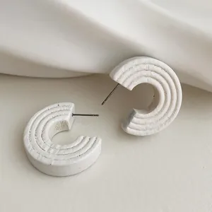 Minimalist white C-shaped hoop earrings with concentric textured layers and silver pins