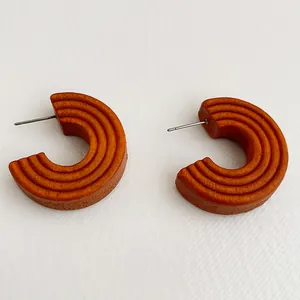 Detail shot of vintage brown C-shaped wooden hoop earrings with fine circular grooves