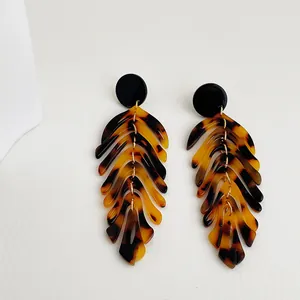 Detail of tortoise shell acrylic leaf earrings with gold chain link and black studs