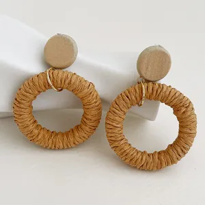 Dettaglio di orecchini in rattan intrecciato a mano con fibra naturale e anello in metallo oro