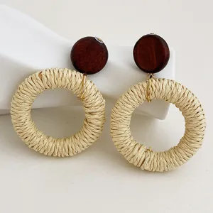 Dettaglio macro di orecchini boho in rattan con borchie in legno su decoro in ceramica