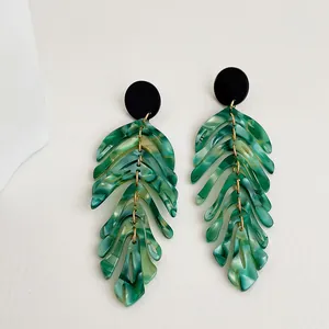 Detailed macro view of tropical leaf earrings with green marble acrylic and gold links