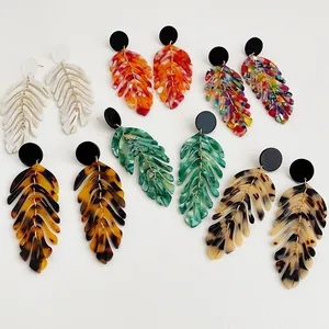 Flat lay showing various colors of acrylic leaf earrings with gold chain fringe
