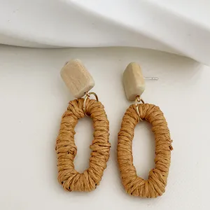 Dettaglio di orecchini in rattan fatti a mano con blocchi di legno e trama intrecciata