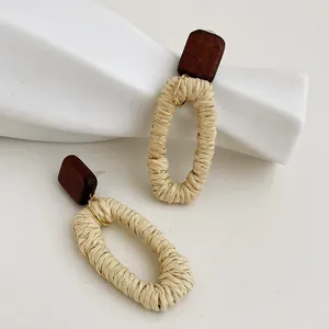 Dettaglio di orecchini in rattan intrecciato a mano con borchie in legno naturale