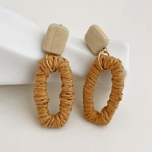 Dettaglio di orecchini boho fatti a mano con blocco di legno e pendente in rattan
