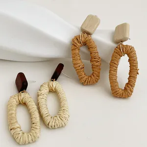 Dettaglio ravvicinato di orecchini boho fatti a mano in legno naturale e rafia intrecciata