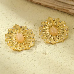 Luxuriöse Blumen-Ohrstecker mit Perle und Edelstein auf strukturierter Steinfläche