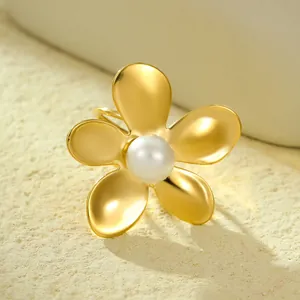 Elegant gold flower ring with pearl center on a textured stone background