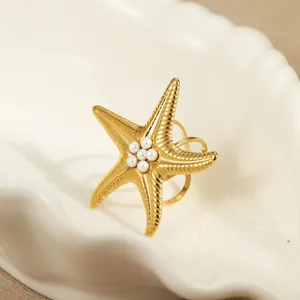 Anello stella marina dorata con perle bianche su vassoio in ceramica a conchiglia