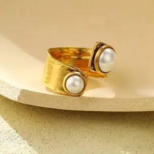Primer plano detallado de un anillo abierto de oro martillado con dos perlas blancas finas