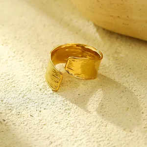 Detail van een brede 18K vergulde titanium ring met onregelmatige gehamerde textuur