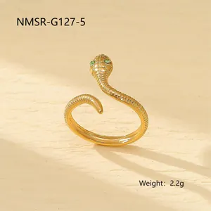 Détail d'une bague serpent avec texture d'écailles et yeux en gemmes vertes dorée