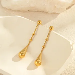 Minimalistische gouden druppeloorbellen met schakelkettingen op witte stenen voet