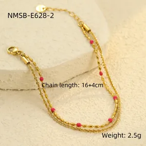 Detail eines 18K vergoldeten doppelten Armbandes mit rosa Perlen auf strukturiertem Stein