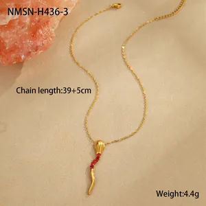 Détail macro du pendentif serpent doré avec zircon rouge sur fond beige texturé