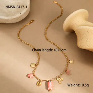 Détail du collier doré océan avec breloques étoile de mer et coquillage sur sable