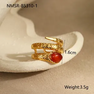Détail macro d'une bague serpent avec gemme rouge et écailles en acier plaqué or