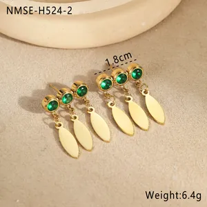 Detail showing gold teardrop earrings with green cubic zirconia on a stone dish