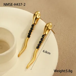 Boucles d'oreilles serpent dorées avec zircons noirs sur un plat en céramique