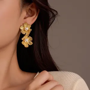 Détail de boucles d'oreilles pétales en or 18k avec perles sur l'oreille du mannequin