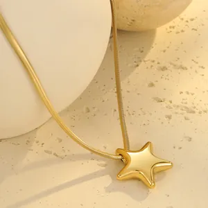 Makroansicht der goldenen Schlangenkette mit Sternanhänger auf Keramikstruktur