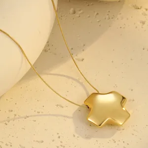 Makroaufnahme des hochglanzpolierten Goldkreuz-Anhängers an einer minimalen Schlangenkette