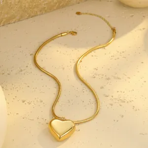 Makroaufnahme von 18k vergoldetem Herzanhänger mit Schlangenkette auf Steinoberfläche