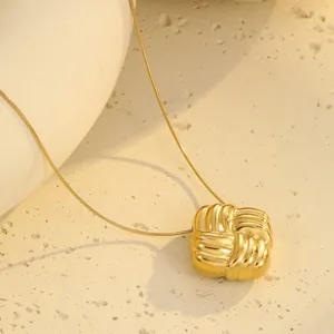 Makroaufnahme des goldenen quadratischen Anhängers mit Webstruktur auf Steinhintergrund
