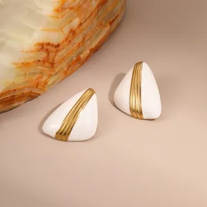 Detail view of triangular white enamel earrings with vertical gold metal stripes