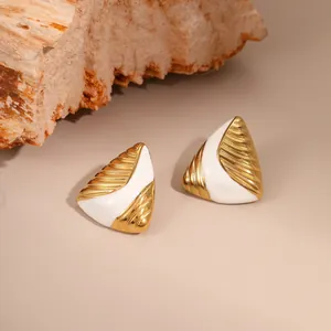 Detail of vintage gold earrings with ribbed texture and white enamel geometric design