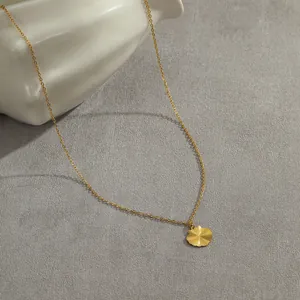 Golden stainless steel necklace featuring a sunburst textured circular pendant on a flat surface