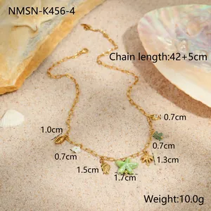 Detailed view of ocean theme gold necklace with starfish and shell charms on beach sand