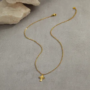 Detail of gold stainless steel cross necklace with sunburst texture on artistic grey stone background