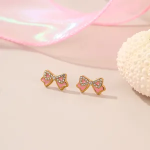 Nahaufnahme von rosa Emaille-Schleifen-Ohrsteckern mit Kristallen in Gold-Finish