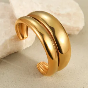 Polished gold wide cuff bracelet with a minimalist double-row design on natural stone