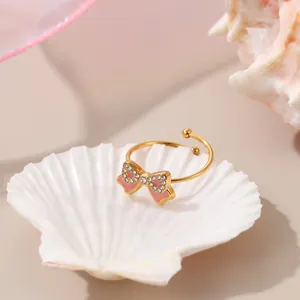 Detail eines verstellbaren goldenen Schleifenrings mit rosa Emaille und Strass