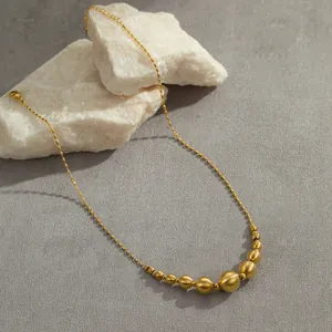 Collier en acier inoxydable doré avec des perles brossées sur un décor de pierre