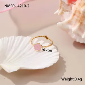 Detail eines Goldrings mit rosa Emailleblume und 0,7 cm Durchmesser auf einer Muschel