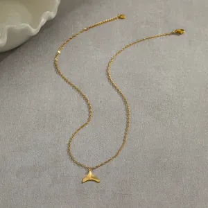 Detail of gold fish tail pendant necklace with radial texture and lobster clasp on grey cloth