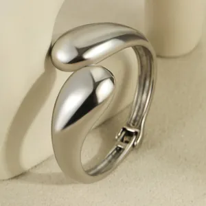 Macro detail of polished stainless steel teardrop hinge on minimalist open bangle