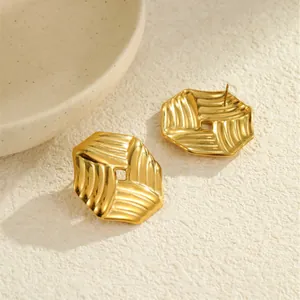 Detailansicht goldene geometrische Ohrstecker mit Wellenstruktur und quadratischer Aussparung